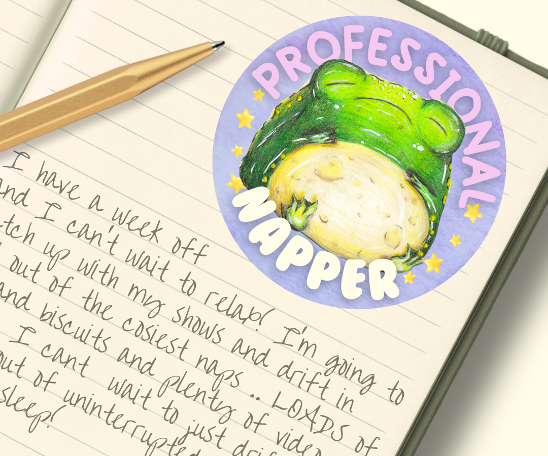 image shows a round purple vinyl sticker, featuring a chubby sleeping toad, around him are the words 'professional napper' and he is surrounded by stars either side of him. The sticker is shown in the image, placed in the top right hand corner of a journal notebook page. Below features a handwritten journal entry and a gold pen