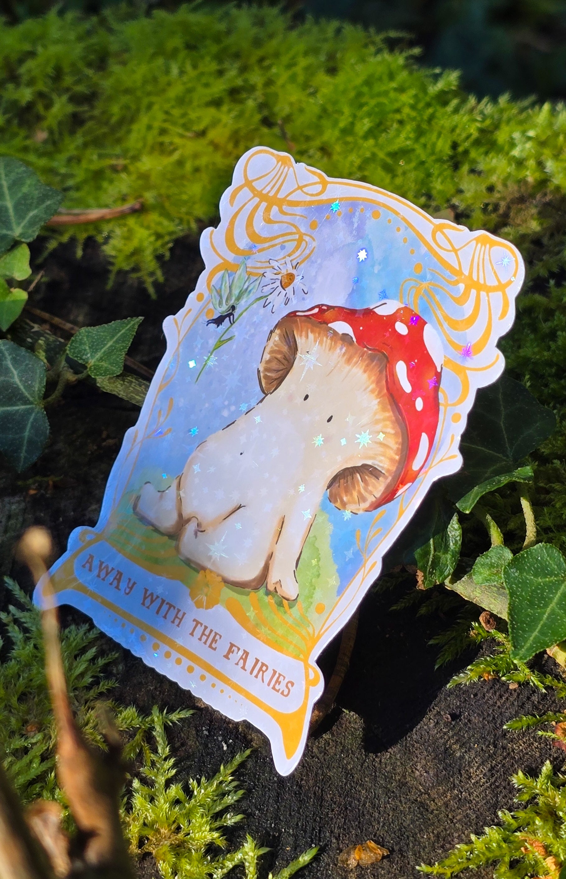 a holographic vinyl sticker with away with the fairies written on it underneath artwork of a toadstool mushroom meeting a fairy who is offering it a daisy