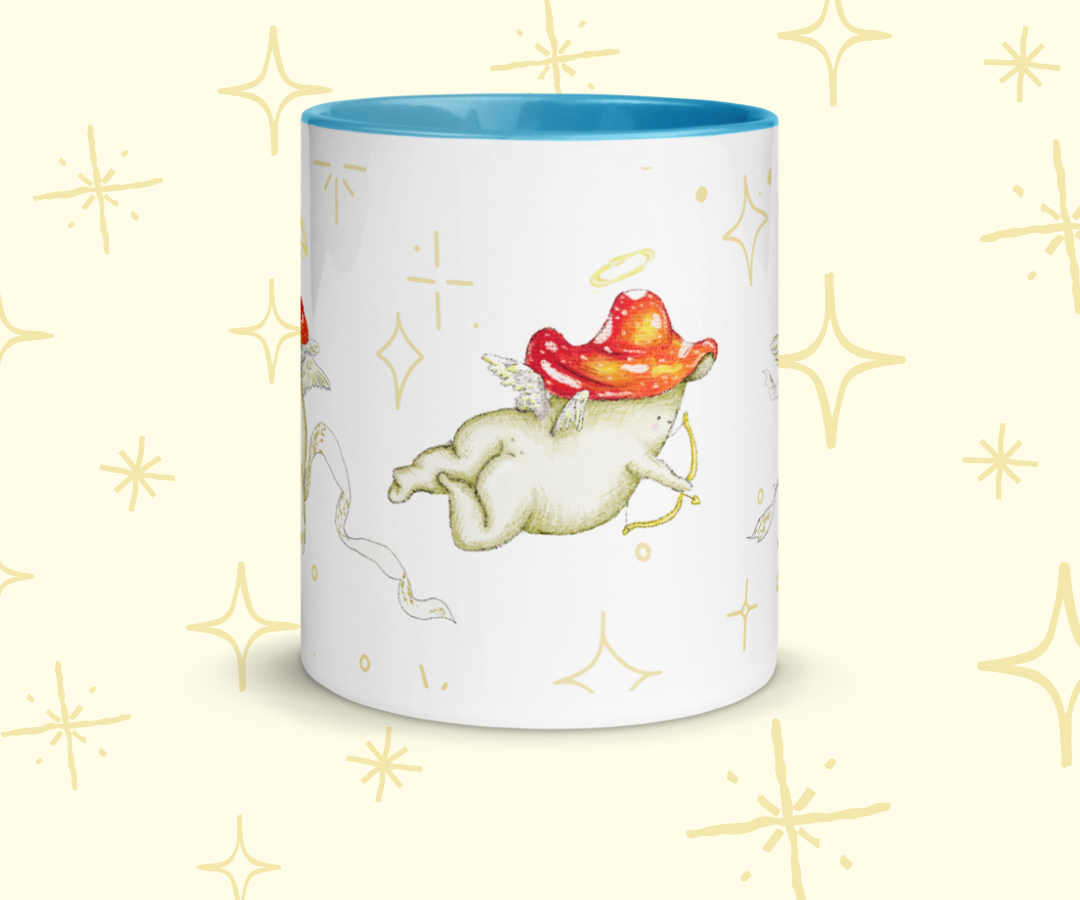 image shows a white ceramic mug which is blue on the uinside, and the handle. The design features illustrations of cherub mushrooms playing instruments and flying amongst a starry backdrop. The mug is imposed in front of a cream background with star graphic details
