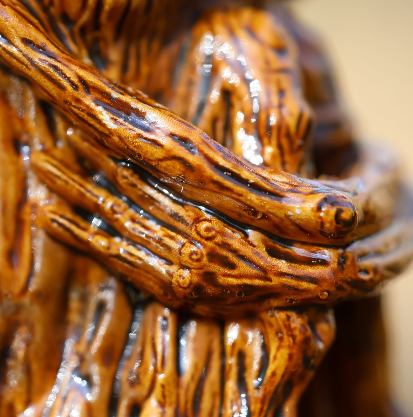 an extreme close up photo  of Splint's arms and hand hugging his knees to his body The photo shows the contrast of paint which is picked up in his tree like details, particularly focusing on spiral details around knuckle and elbow joints