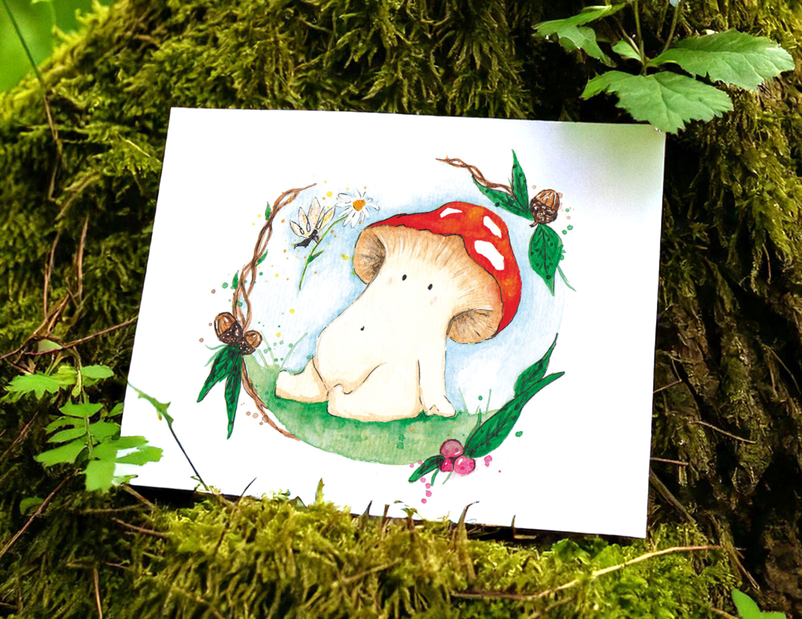 An art print lays against a mossy tree stump in a forest. The water colour illustration is of a toadstool mushroom meeting a fairy. the fairy is offering a daisy