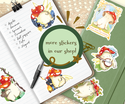 image shows two journals, one opened with shopping list and pen laid on the open page, various designs of Mushroom vinyl sticker are shown placed on the journals. A graphic in the centre of the image reads, 'More stickers in our shop!'